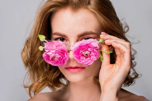 Beautiful girl wearing eyeglasses with flowers and looking at camera isolated on grey — Stock Photo