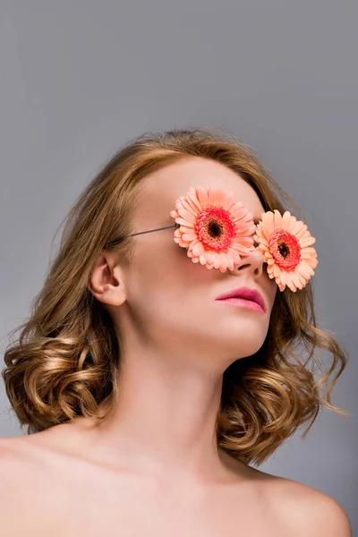 Low angle view of naked girl wearing glasses with flowers isolated on grey — Stock Photo