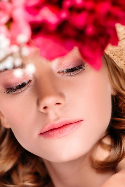 Selective focus of young woman wearing hat with flowers and looking down — Stock Photo