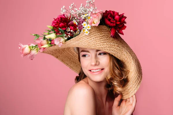 Beautiful smiling naked girl wearing wicker hat with flowers isolated on pink — Stock Photo