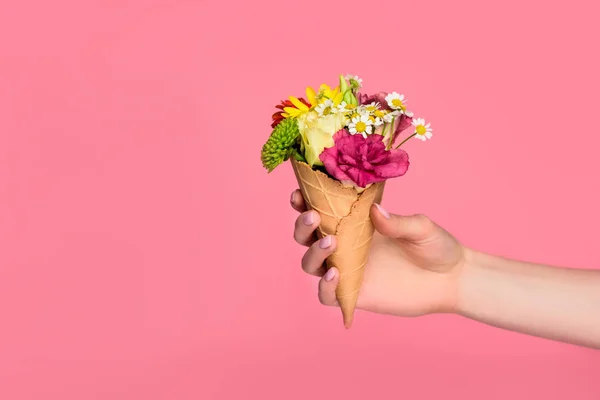 Cropped shot of girl holding ice cream cone with beautiful flowers isolated on pink — Stock Photo