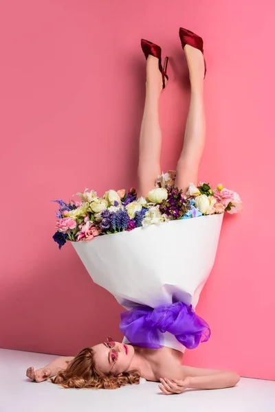 Upside down view of beautiful young woman with fresh flowers in dress on pink — Stock Photo