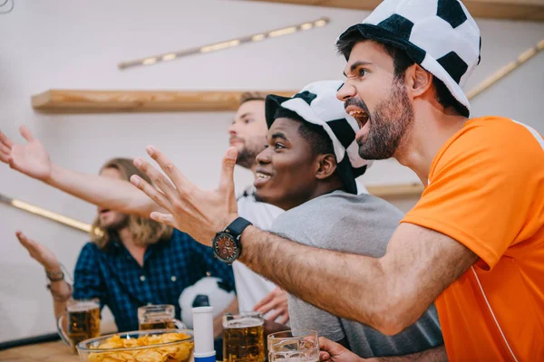 Grupo multicultural emocional de fãs de futebol masculino gesticulando por mãos e assistindo jogo de futebol no bar — Fotografia de Stock