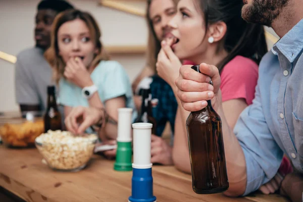 Close up view of fan horns on bar counter and group of friends with beer bottles watching soccer match — Stock Photo