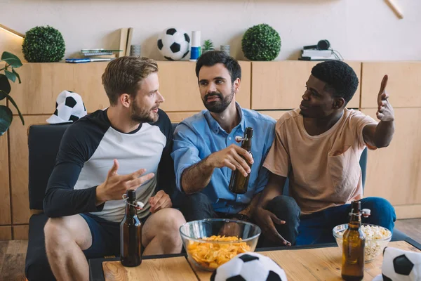 Gestos amigos multiculturales hablando durante el reloj del partido de fútbol en casa - foto de stock