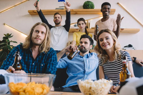 Fröhliche multikulturelle Freunde, die zu Hause Bier trinken und Fußballspiele gucken — Stockfoto