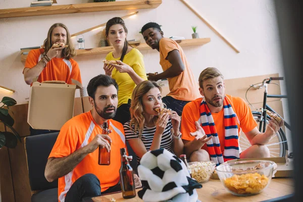 Amici multiculturali con pizza e birra guardando partita di calcio a casa — Foto stock