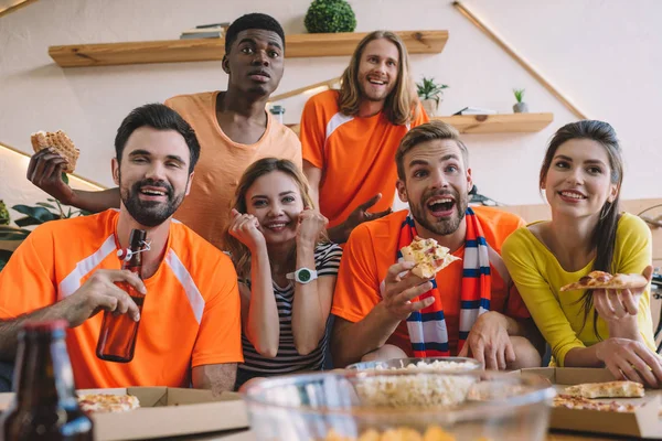 Gruppo di amici multiculturali con pizza e birra guardando la partita di calcio a casa — Foto stock