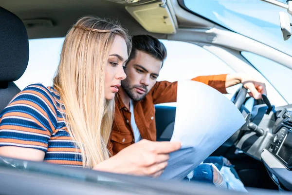 Vista de perto do jovem casal sentado no carro e olhando para o mapa — Fotografia de Stock