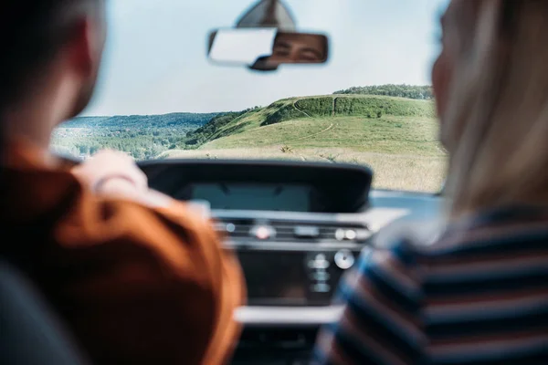 Visão traseira do jovem casal sentado no carro no prado rural — Fotografia de Stock