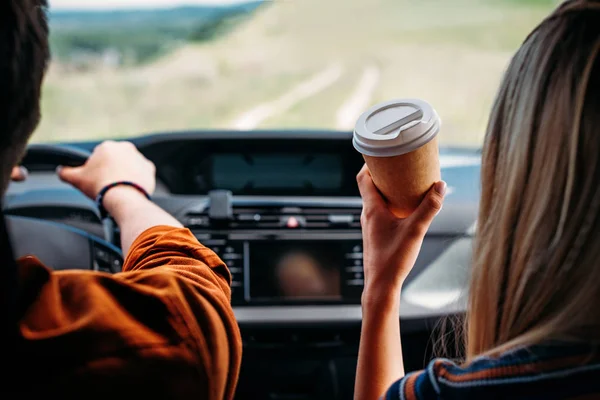 Частковий вид чоловіка, що водить машину, а його дівчина сидить поруч з паперовою чашкою кави — стокове фото
