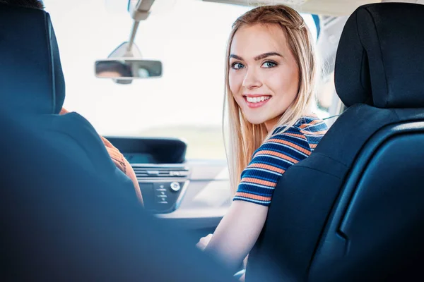 Jovem sorrindo mulher olhando para a câmera enquanto seu namorado carro de condução — Fotografia de Stock