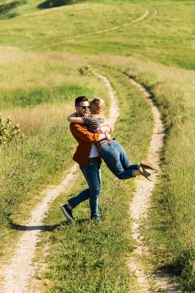 Alto ángulo vista de hombre joven girando alrededor de novia en campo rural - foto de stock