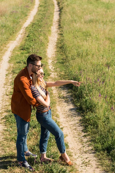 Seitenansicht eines Mannes, der Freundin umarmt, während sie mit dem Finger auf ihn zeigt — Stockfoto