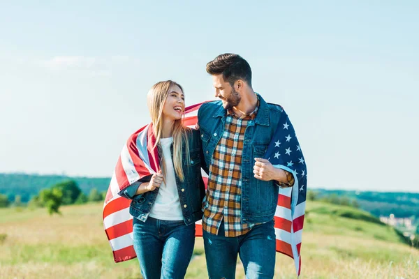 Couple élégant avec drapeau américain sur prairie rurale, concept de fête de l'indépendance — Photo de stock