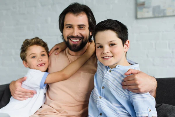 Portrait of happy family hugging each other and looking at camera at home — Stock Photo