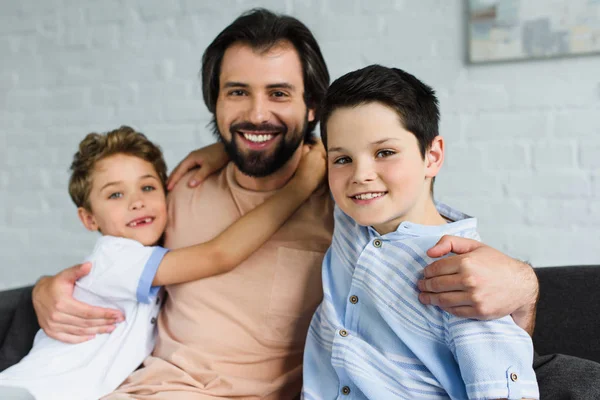 Ritratto di una famiglia felice che si abbraccia e guarda la macchina fotografica a casa — Foto stock