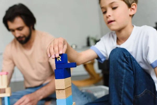 Messa a fuoco selettiva di padre e figlio che giocano con blocchi di legno insieme a casa — Foto stock