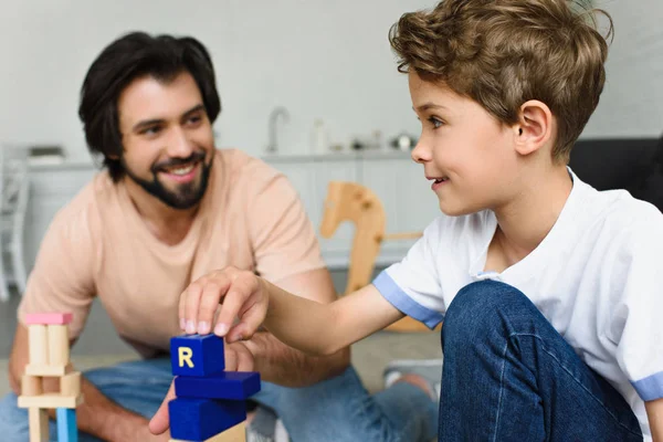Selective focus of father and son playing with wooden blocks together at home — Stock Photo