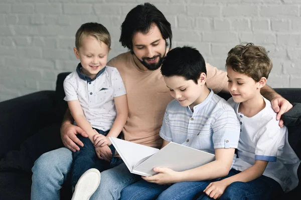 Портрет отца и сыновей, читающих книгу вместе дома — стоковое фото