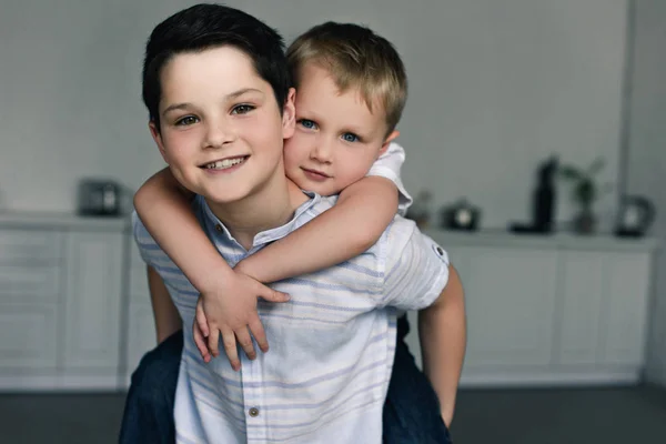 Portrait of happy brothers piggybacking together at home — Stock Photo