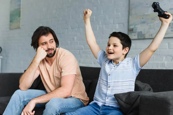 Отец и счастливый сын вместе играют в видеоигры дома — стоковое фото