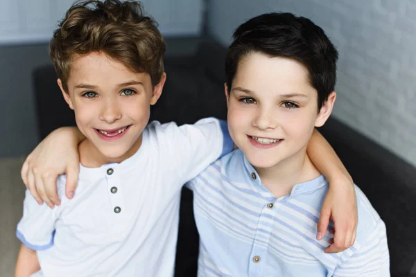 Retrato de hermanos felices abrazándose en casa - foto de stock