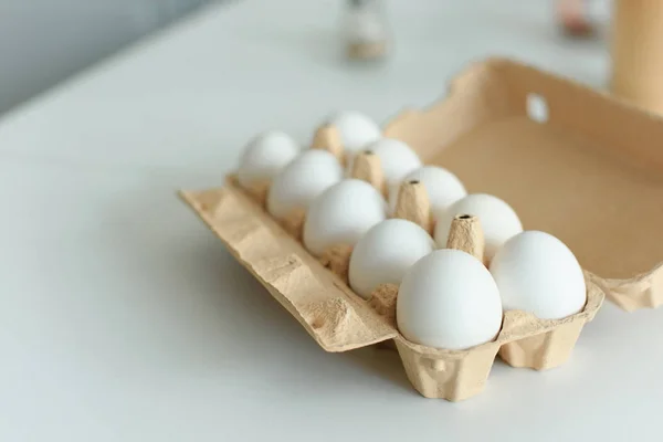 Primer plano vista de huevos de pollo crudos en caja en la mesa en la cocina - foto de stock