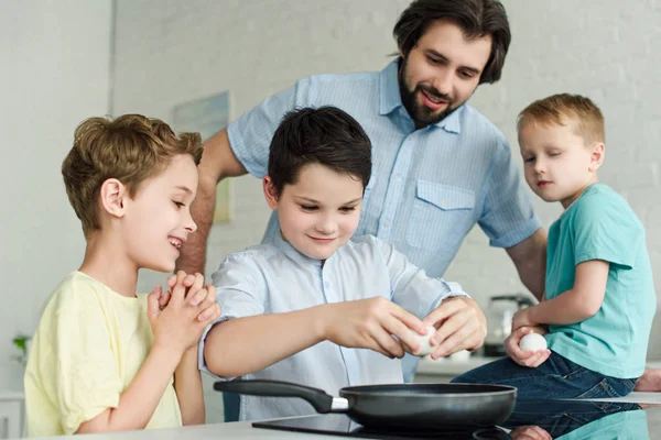 Portrait of family cooking eggs for breakfast together in kitchen at home — Stock Photo