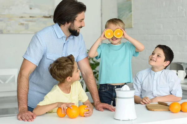 Familia haciendo zumo de naranja fresco en la cocina en casa - foto de stock