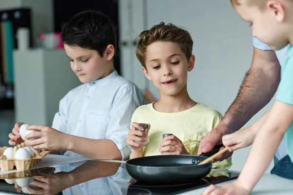 Partial view of family cooking eggs for breakfast together in kitchen at home — Stock Photo