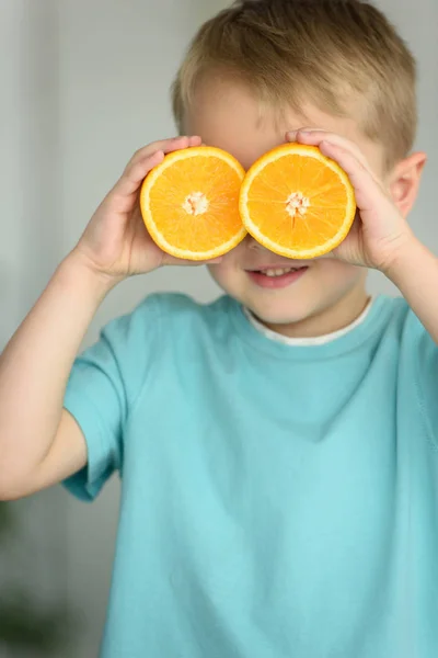 Vista oscurata di bambino che copre gli occhi con pezzi di arancia fresca in mano — Foto stock