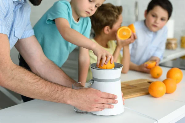 Teilansicht der Familie, die in der heimischen Küche frischen Orangensaft zubereitet — Stockfoto