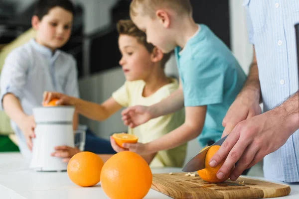 Частковий вид на сім'ю, що робить свіжий апельсиновий сік на кухні вдома — стокове фото