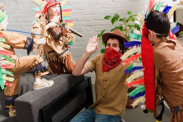 Homme en chapeau et bandana rouge jouant avec des fils en costumes autochtones à la maison — Photo de stock