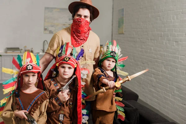 Porträt kleiner Jungen in indigenen Kostümen und Vater mit Hut und rotem Kopftuch, der zu Hause in die Kamera blickt — Stockfoto