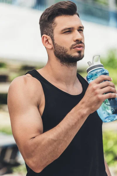 Schöner junger Sportler trinkt Wasser aus der Flasche — Stockfoto