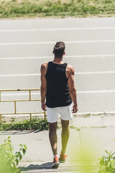 Visão traseira do jovem corredor masculino indo na pista de corrida — Fotografia de Stock