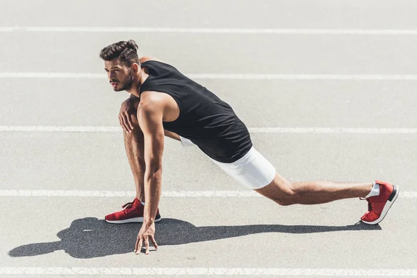 Jogger maschile che si estende sulla pista da corsa al parco giochi sportivo — Foto stock