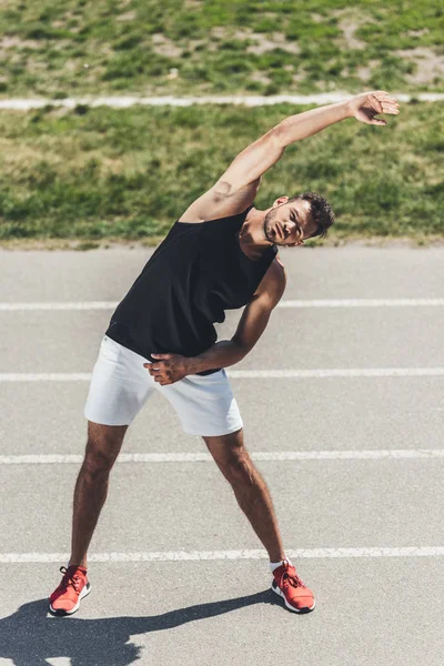 Athlète masculin faisant de l'exercice sur piste de course au terrain de jeu sportif — Photo de stock