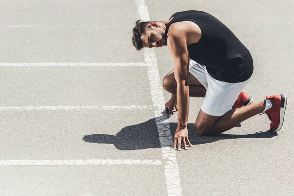 Giovane sportivo in partenza bassa su pista da corsa — Foto stock