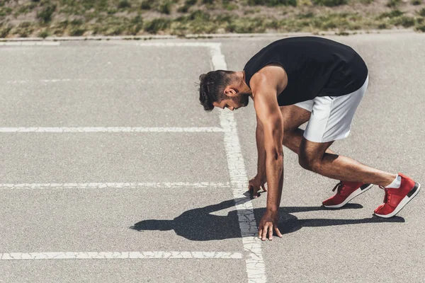 Серйозний юний спортсмен на низькому старті на біговій доріжці — стокове фото