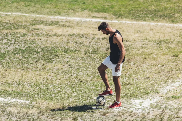 Giocatore di calcio maschile con pallone da calcio al campo da giuoco — Foto stock