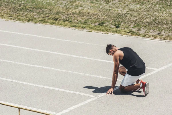 Side view of male sprinter in starting position on running track — Stock Photo