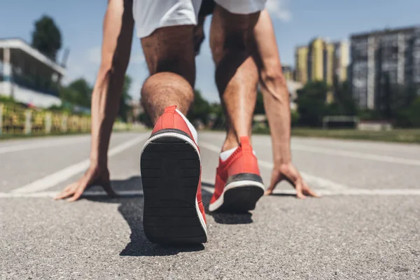 Back view of male sprinter in starting position on running track — Stock Photo