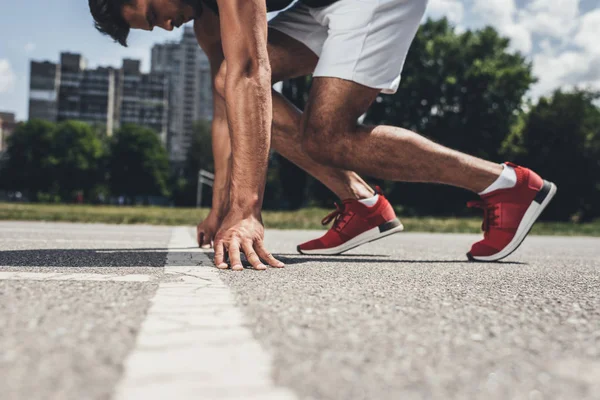 Teilsicht männlicher Sprinter in Startposition auf Laufstrecke — Stockfoto