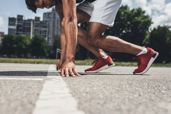 Partial view of male sprinter in starting position on running track — Stock Photo