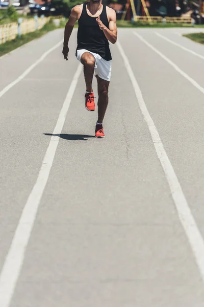 Tiro recortado do atleta masculino jogging na pista de corrida no parque desportivo — Fotografia de Stock