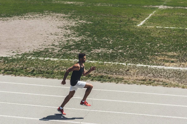 Vista de ángulo alto del velocista masculino en pista de atletismo en el parque infantil deportivo - foto de stock