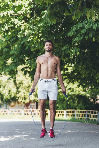 Sporty shirtless young man working out with jumping rope — Stock Photo